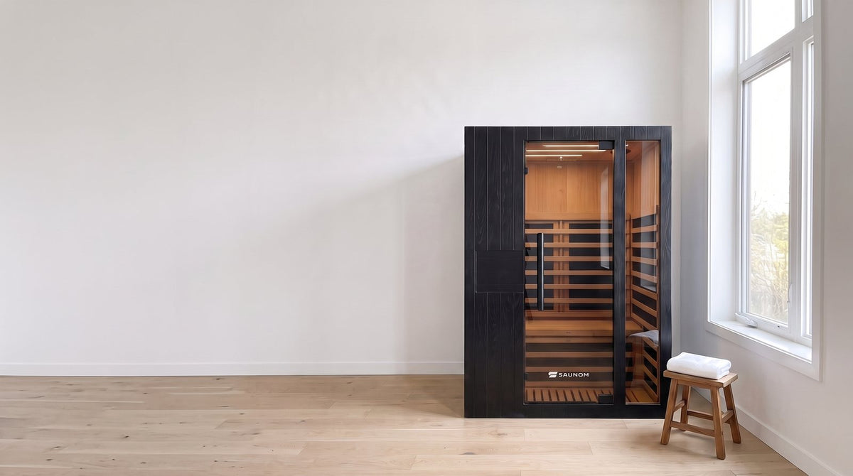 Black Saunom infrared sauna in a calm spare room next to a wooden stool