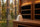 A cream wool Havu sauna hat resting on the bench of a modern infrared sauna cabin with dark infrared heater panels behind it.