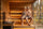 A woman in a dry cream wool sauna hat and a man in a grey wool beanie relaxing on the top bench of a hot traditional sauna.