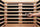 A hand holding a small EMF meter a few inches from a flat heater panel inside a bright infrared sauna cabin.