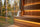 A white felted wool Havu sauna hat resting on the cedar bench of a warm Finnish sauna with a forest view.
