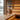 SAUNOM sauna cleaner bottle on a wooden sauna bench with warm LED lighting and forest lake view through the window