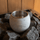 Close-up of a grey soapstone aromatherapy cup sitting among hot sauna heater stones with light steam rising