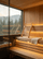 Wooden sauna backrest on a modern sauna bench with warm lighting and mountain forest view