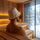 Person sitting in a wooden sauna with a sauna bucket hat on their head, looking out of a window at snowy trees.