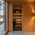 A modern wooden sauna with a clear glass door, warm interior lighting, and wooden benches, set against a wood-paneled exterior wall with a window showing an outdoor lakeside view.