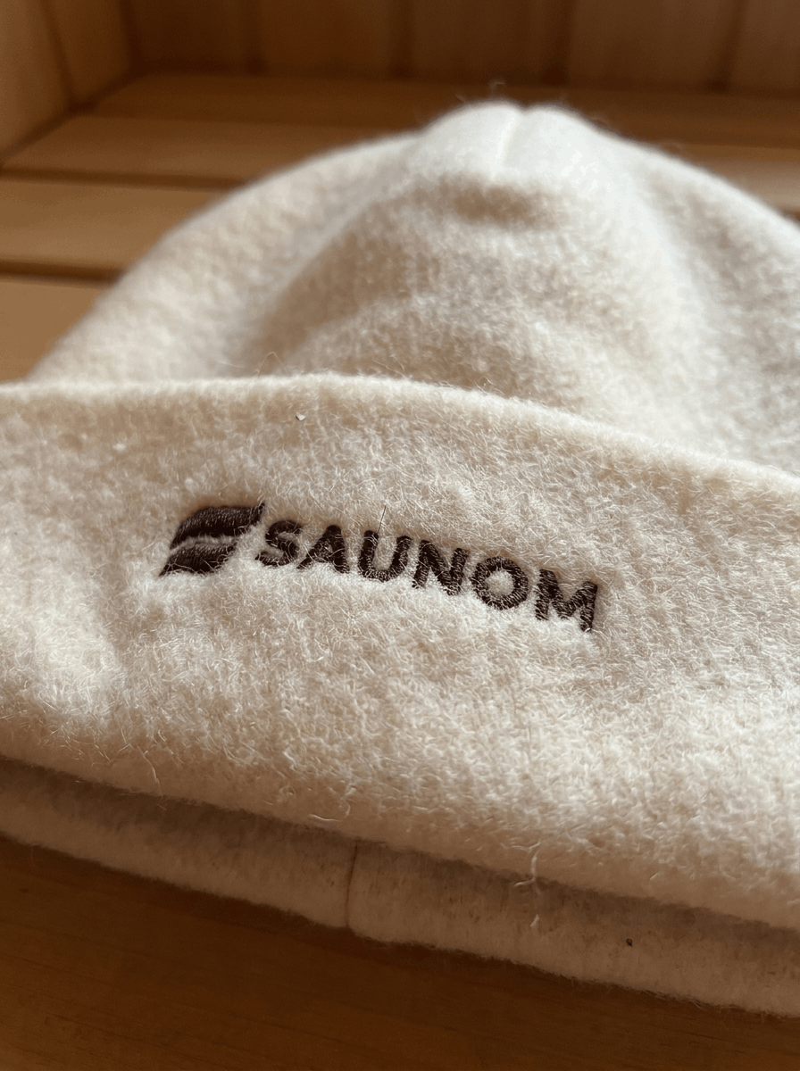 Close-up of embroidered logo on a white wool sauna hat