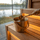 Gold SAUNOM sauna bucket filled with water with a matching ladle held above it inside a lake-view sauna