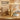 A gold-toned sauna bucket with a bamboo handle and ribbon, shown with a matching bamboo ladle, folded white towel, and kraft gift box on a wooden table. Promotional text reads 'The Perfect Sauna Gift' and highlights thoughtful packaging and ease of cleaning.