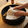 White wool sauna hat being gently hand washed in a black sink
