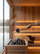 SAUNOM sauna ladle pouring water onto hot sauna stones with matching bamboo-handled bucket resting on the bench