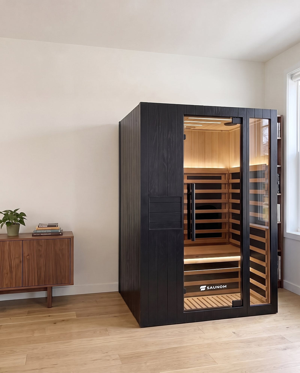 Black Saunom infrared sauna in a living room next to a walnut sideboard