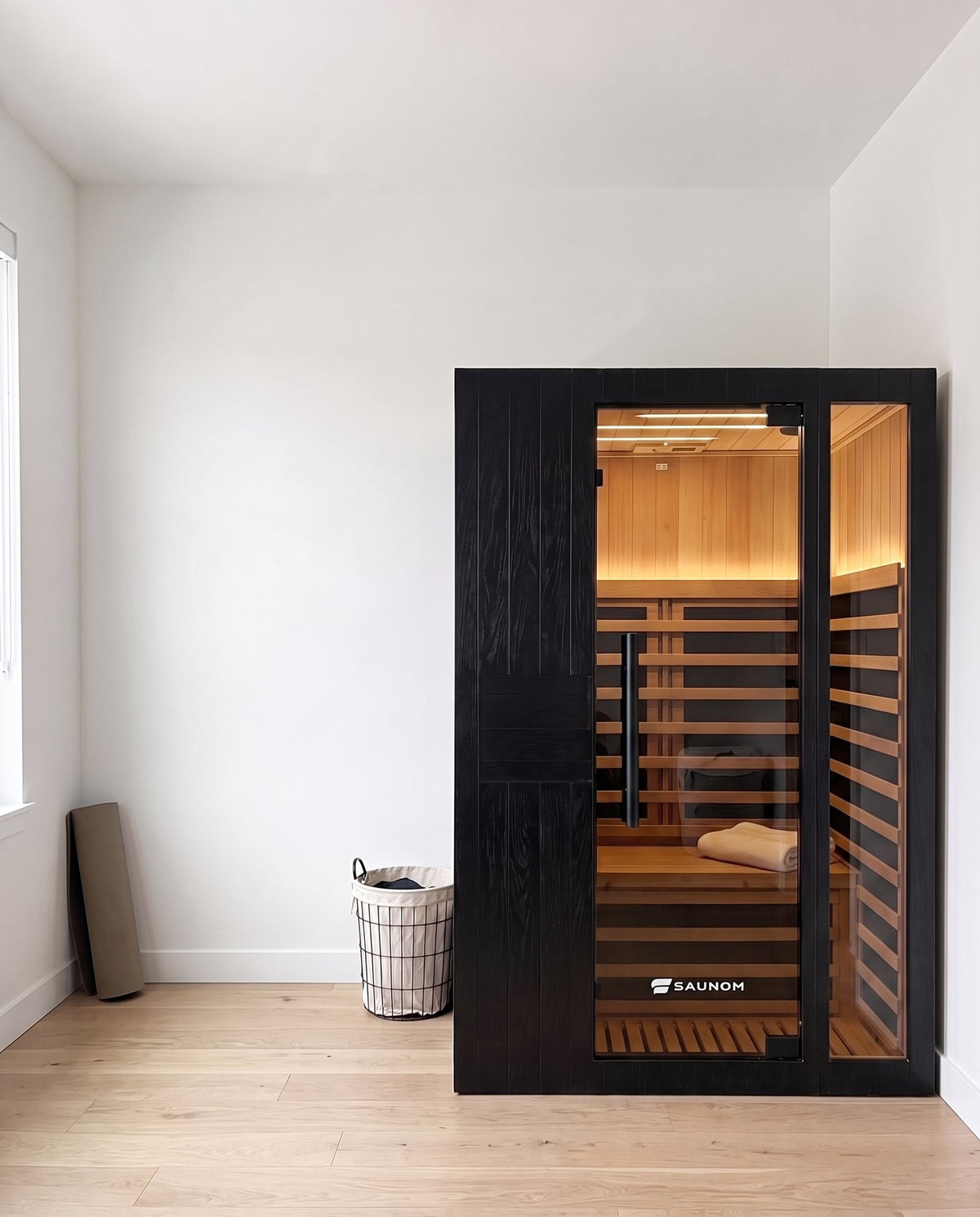 Black Saunom infrared sauna with the door closed in a bright spare room