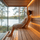 Man reclining comfortably in a modern sauna using a SAUNOM ergonomic wooden backrest