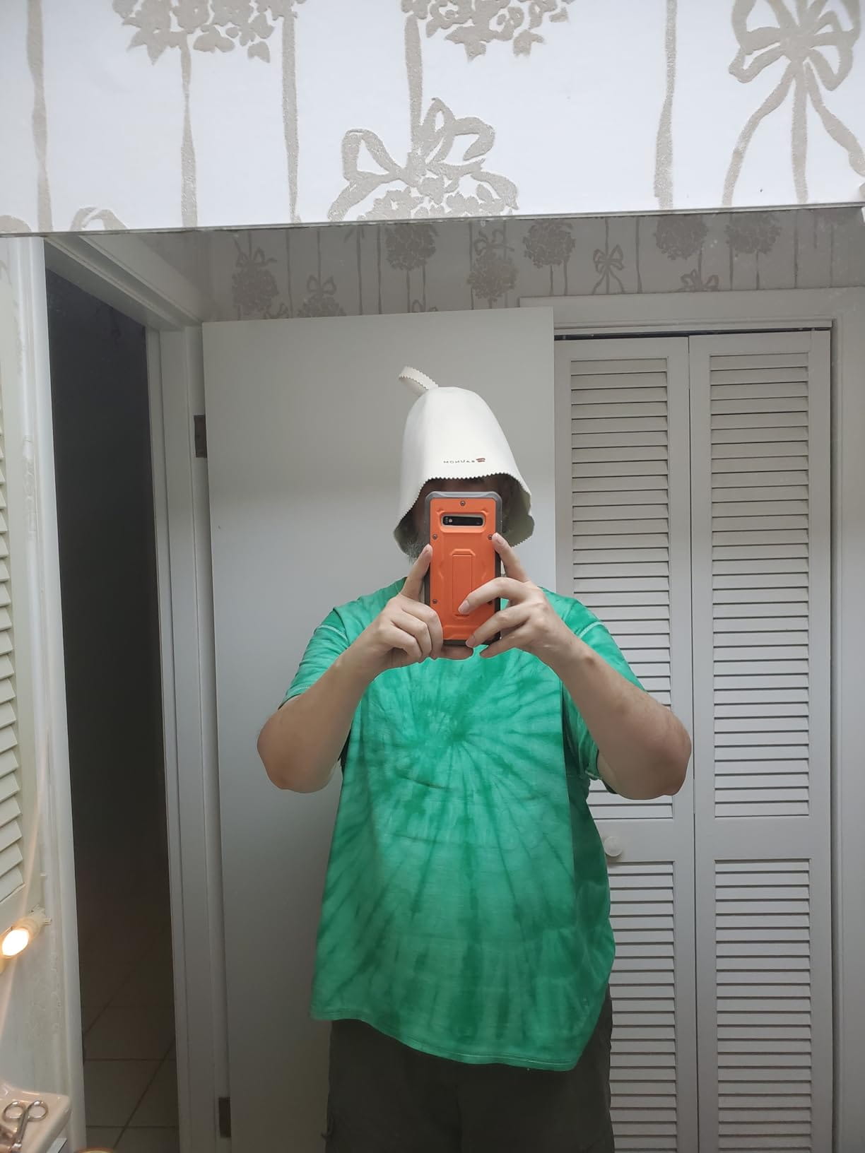 Person taking a mirror selfie while wearing a white wool sauna hat