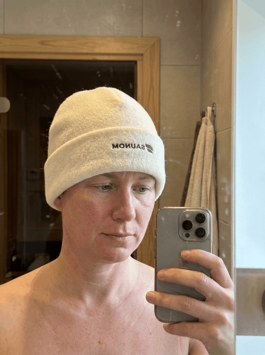 Person taking a mirror selfie while wearing a white wool sauna hat