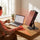 Woman using SAUNOM red light therapy panel at her desk during a morning routine