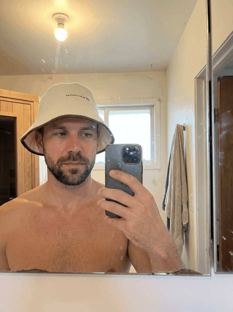 Man wearing a white bucket-style sauna hat before a sauna session