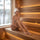 Woman sitting peacefully on a wooden sauna bench while wearing a white sauna hat