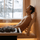 Man resting with eyes closed in a sauna, supported by a SAUNOM curved wooden backrest near the heater