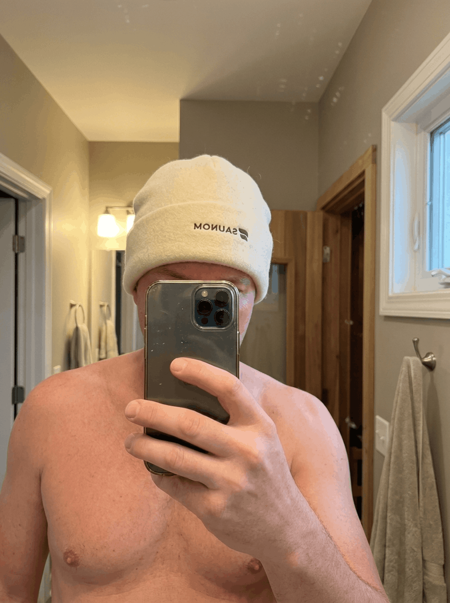 Man taking a mirror selfie while wearing a white wool sauna hat