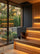 Anodized sauna bucket and wooden ladle placed on a bench inside a modern sauna with garden view