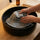 Grey wool bucket-style sauna hat being gently hand washed in a black sink
