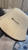 Close-up of a white wool sauna hat with embroidered SAUNOM logo and stitched edge