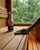 A gloved hand wiping sauna wood beside Saunom cleaner spray
