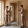 Two installers fitting an alder-framed clear glass sauna door into a wood-paneled sauna opening