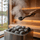 Water being poured from a sauna ladle onto rounded heater stones with steam rising
