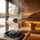 Gold SAUNOM ladle pouring water onto sauna rocks with steam rising inside a modern wooden sauna