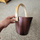 Dark anodized sauna bucket with wooden handle and SAUNOM logo