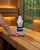 A hand wiping a sauna bench with Saunom sauna cleaner, lifting sweat and body oil from the wood