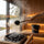 Water poured from a black SAUNOM ladle onto sauna stones to create steam, with the matching bucket behind.