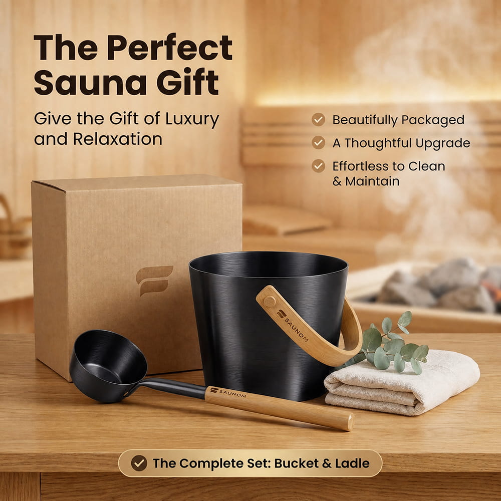 SAUNOM black sauna bucket and ladle gift set displayed with branded cardboard packaging, a folded towel and eucalyptus.