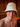 Man smiling inside a wooden sauna while wearing a white bucket-style sauna hat