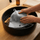 Grey wool sauna hat being gently hand washed in a black sink
