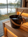 SAUNOM sauna bucket filled with water and matching ladle resting inside on a warm wooden sauna bench