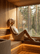Woman relaxing in a wooden sauna while wearing a white merino wool sauna hat