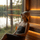 Woman relaxing in a lakeside sauna while wearing a grey wool sauna hat